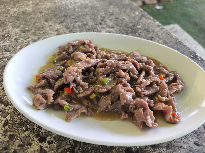 เนื้อผัดน้ำมันหอยใส่พริกขี้หนู บนจานรีสีขาว