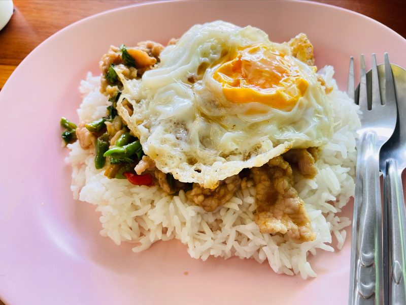 ผัดกะเพราราดข้าว โปะไข่ดาว บนจานสีชมพู