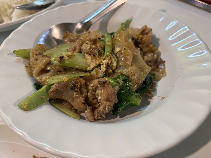 เส้นใหญ่ผัดกับเนื้อ ไข่ และผักคะน้า บนจานขาว